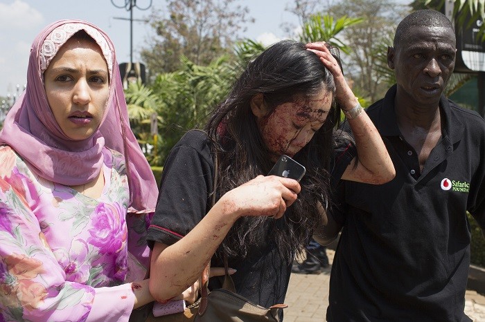 An injured woman (C) is helped out of the Westgate Shopping Centre where gunmen went on a shooting spree, in Nairobi September 21, 2013