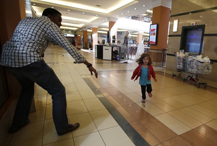 A child runs to safety as armed police hunt gunmen who went on a shooting spree at Westgate shopping centre in Nairobi September 21, 2013.