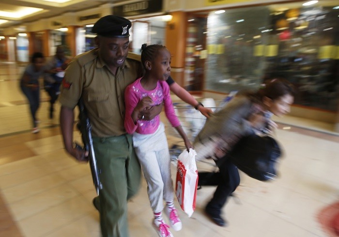 A soldier carries a child to safety as armed police hunt gunmen who went on a shooting spree at Westgate shopping centre in Nairobi, September 21, 2013.